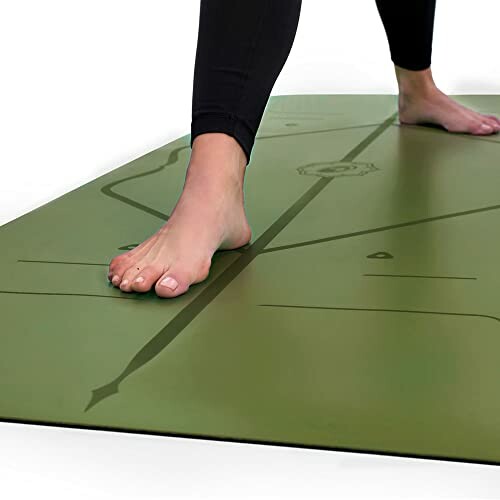 Person standing on a green yoga mat with alignment markings.